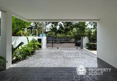 Spacious modern driveway with lush greenery and secure gate access