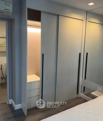 Modern bedroom with sleek built-in wardrobe and mirrored sliding doors, showcasing contemporary design and efficient storage.