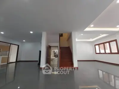 Spacious modern living room with sleek tile flooring and elegant staircase