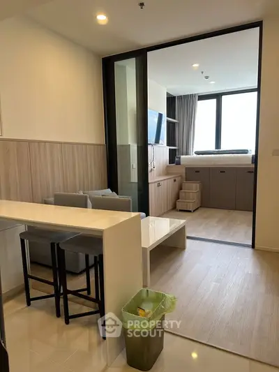 Modern studio apartment with open layout and stylish furnishings, featuring a cozy living area and large window.
