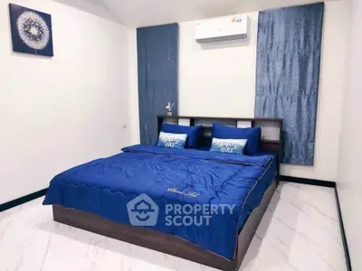 Modern bedroom with blue bedding and wall-mounted air conditioner