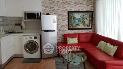 Modern living room with red sectional sofa, washing machine, and stylish kitchen area.