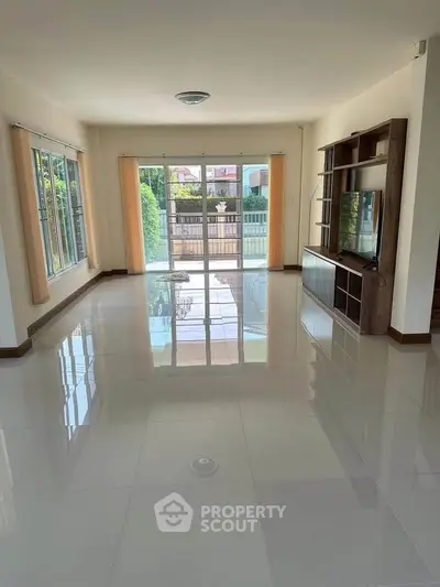 Spacious living room with large windows and glossy tiled floors, perfect for natural light and modern living.