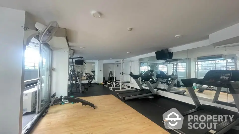 Modern gym with state-of-the-art equipment and spacious layout in luxury apartment building.