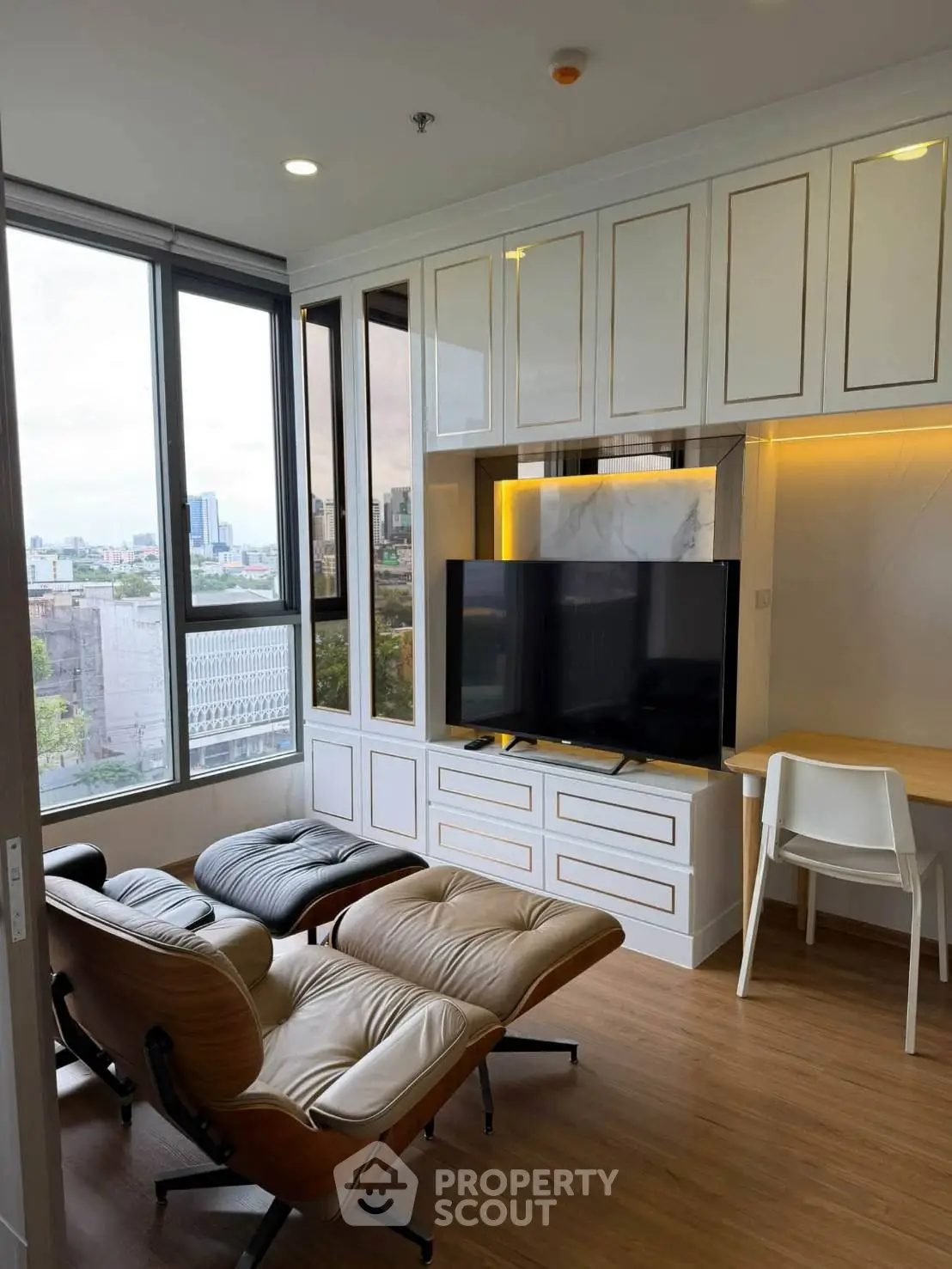 Modern living room with city view, featuring stylish seating and built-in entertainment center.