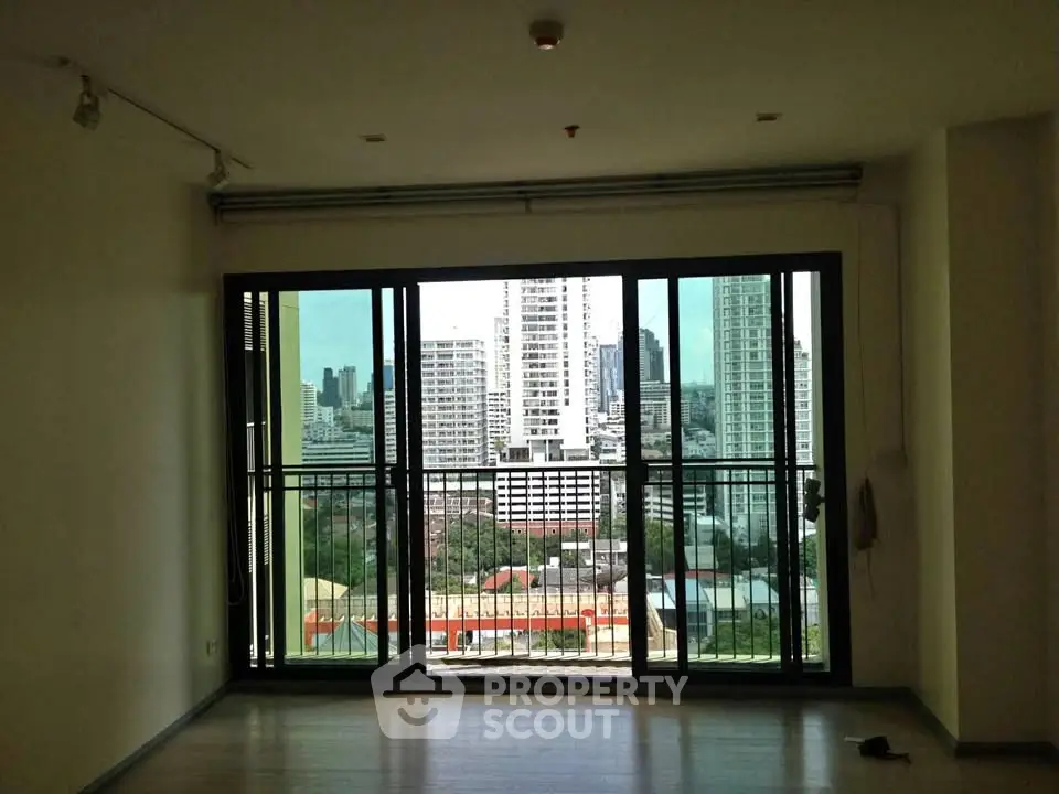 Spacious living room with large windows offering stunning city views in a modern apartment.