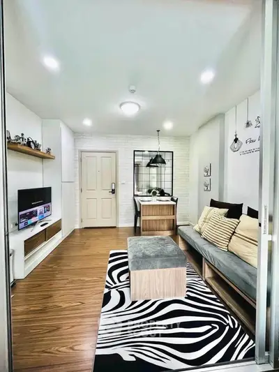 Modern living room with stylish decor and open layout, featuring a cozy sofa and zebra-patterned rug.