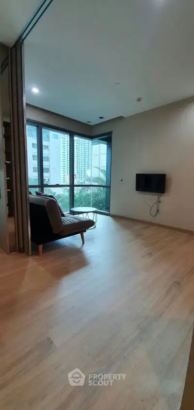 Spacious living room with large windows and modern decor in urban apartment