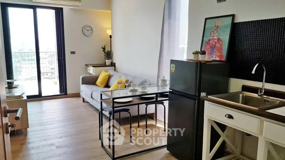 Modern open-layout living room with kitchen and balcony view, featuring stylish decor and natural light.