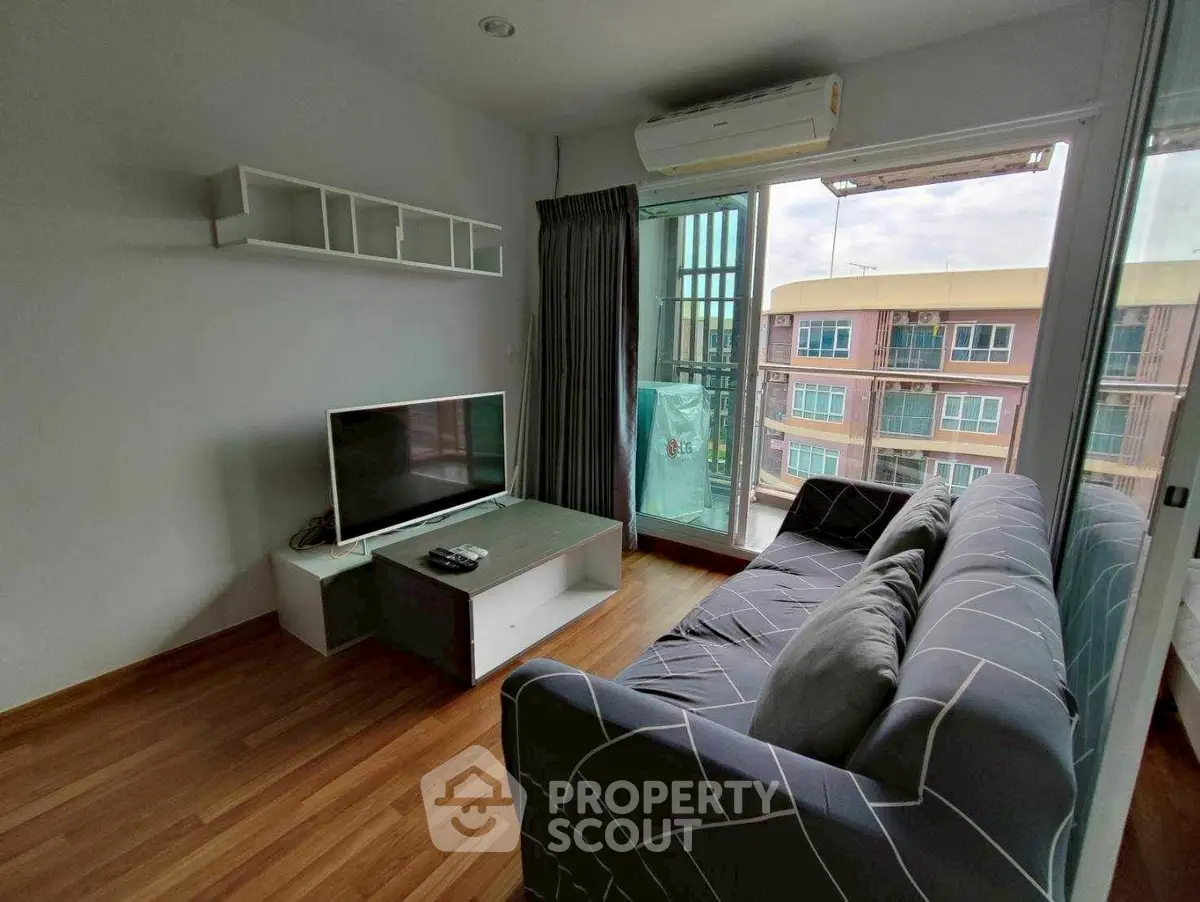Cozy living room with modern decor and balcony view in urban apartment.