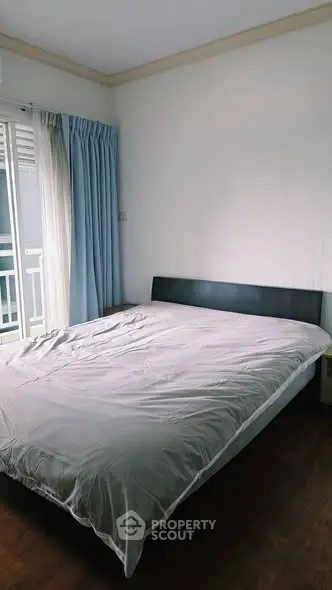 Cozy bedroom with large window and natural light, perfect for relaxation and comfort.