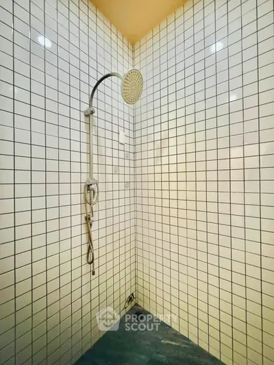 Modern shower area with sleek white tiles and rainfall showerhead, perfect for a contemporary bathroom.