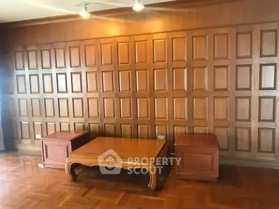 Elegant wooden interior with parquet flooring and panelled walls, featuring a classic coffee table.