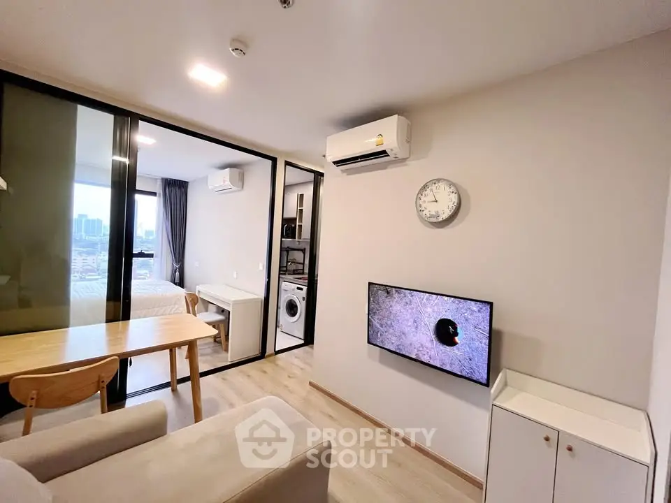 Modern living room with open layout and city view, featuring air conditioning and wall-mounted TV.
