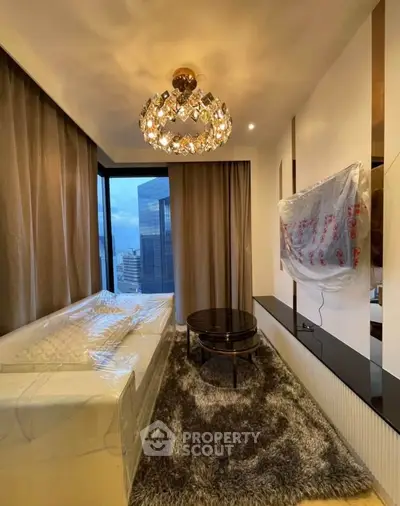 Luxurious living room with modern chandelier and city view, featuring plush carpet and sleek furniture.