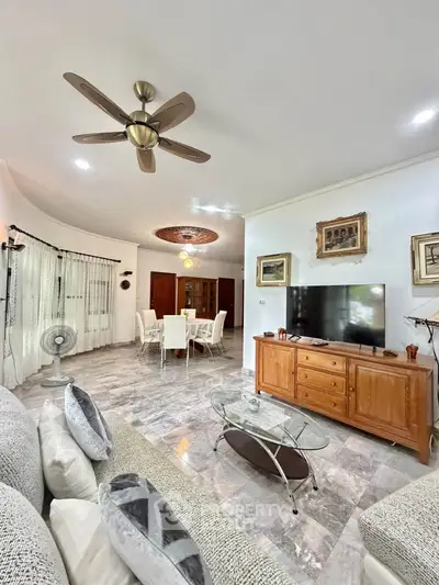 Spacious living room with elegant decor and dining area, featuring modern ceiling fan and large TV.