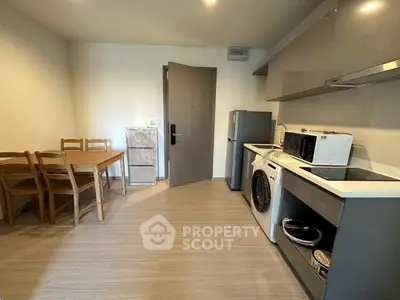 Modern kitchen with dining area, featuring washing machine and microwave, perfect for compact living.