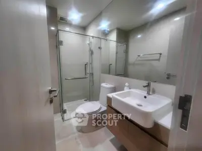 Modern bathroom with glass shower, sleek sink, and contemporary fixtures.