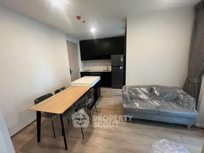 Modern open-layout living room with kitchen, featuring sleek furniture and natural light.