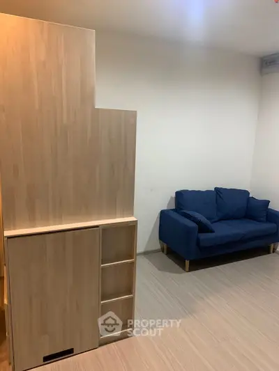 Modern living room with wooden storage and blue sofa, minimalist design.
