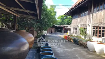 Charming traditional wooden building with decorative pottery and lush greenery.