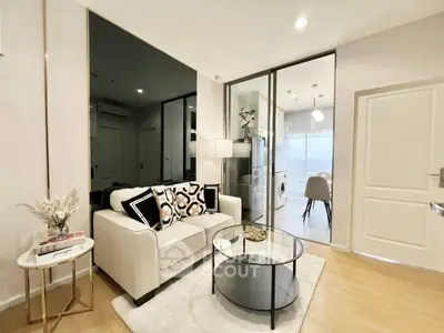 Modern living room with elegant decor and glass partition leading to a bright kitchen area.