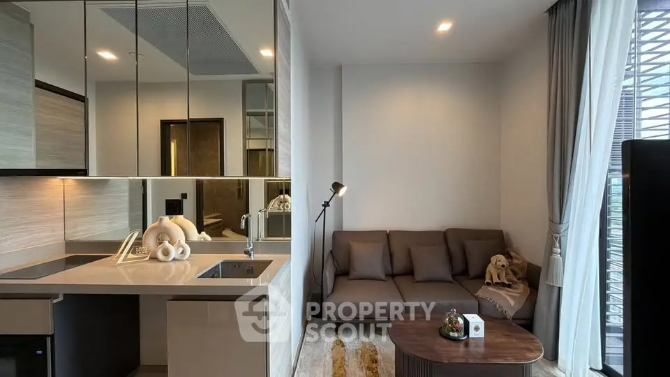 Modern living room with sleek kitchen, cozy sofa, and stylish decor in a contemporary apartment.