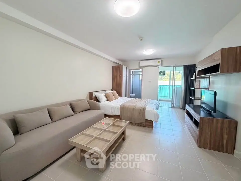 Spacious studio apartment with modern furnishings and balcony view.