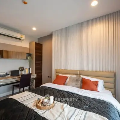 Modern bedroom with stylish decor and workspace, featuring cozy bedding and elegant lighting.