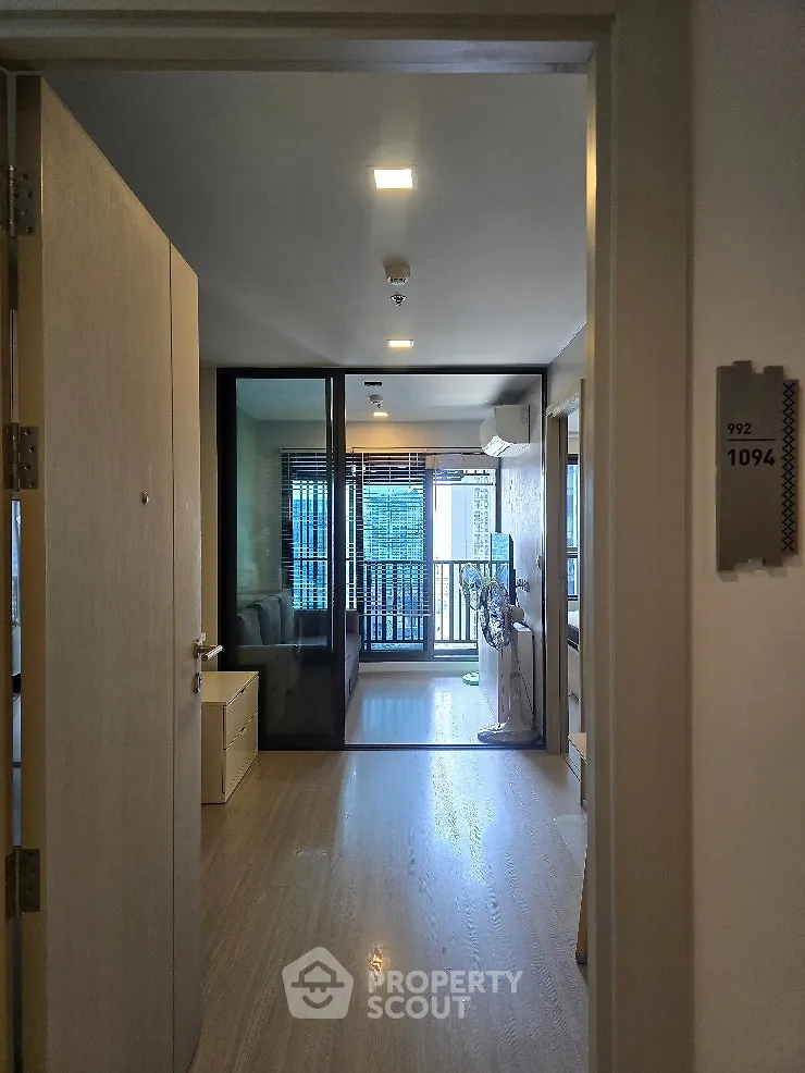 Modern apartment entrance with glass doors leading to a bright living area and balcony view.
