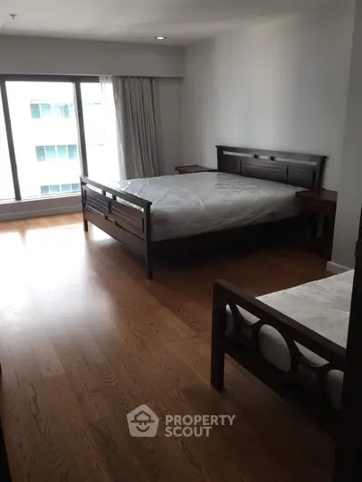 Spacious bedroom with wooden flooring and large windows in modern apartment