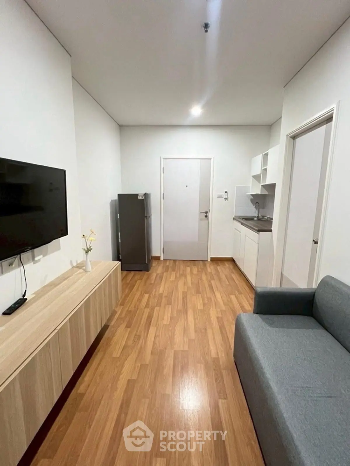 Modern living room with sleek furniture and compact kitchen in a cozy apartment.