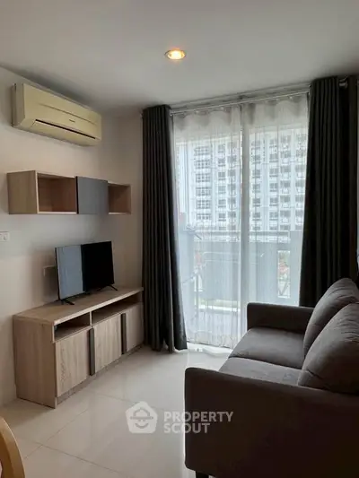 Modern living room with large window and city view, featuring sleek furniture and air conditioning.