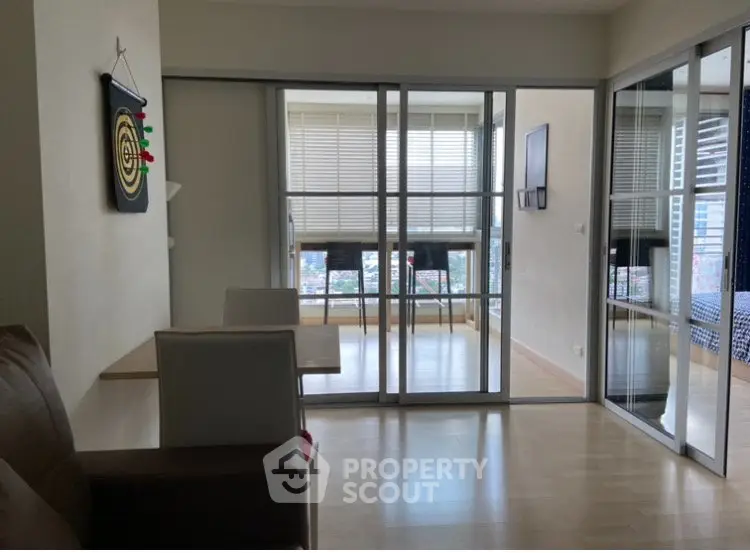 Modern apartment with glass sliding doors and city view, featuring a cozy dining area and bright interior.