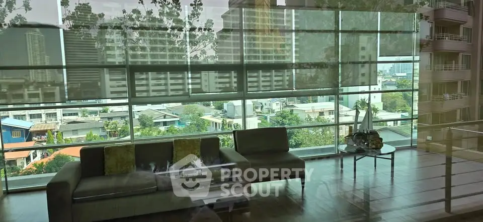 Spacious living room with floor-to-ceiling windows offering stunning city views.