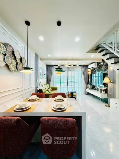 Modern open-plan living room with stylish decor and dining area, featuring elegant lighting and a cozy ambiance.