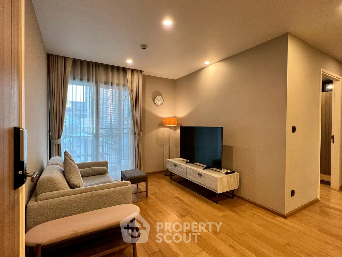 Modern living room with wooden flooring, stylish furniture, and large window with city view.