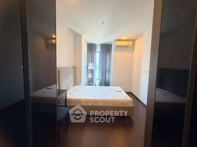 Spacious bedroom with large window and modern furnishings in a stylish apartment.