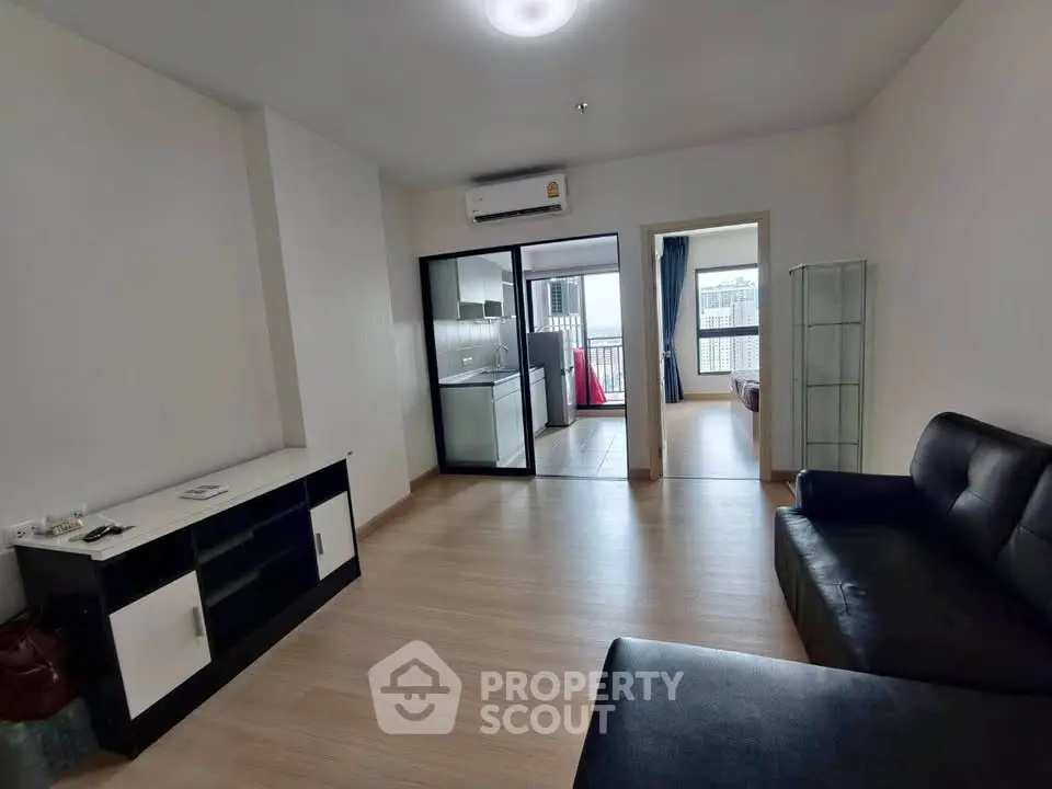 Modern living room with sleek furniture and open layout leading to balcony with city view.