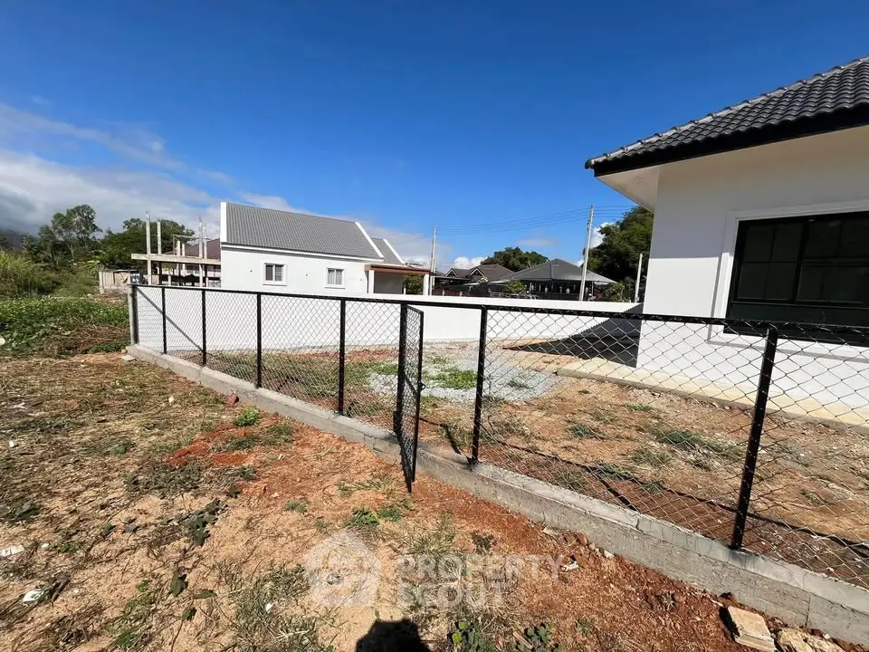 Charming residential property with fenced yard and modern architecture under clear blue skies.