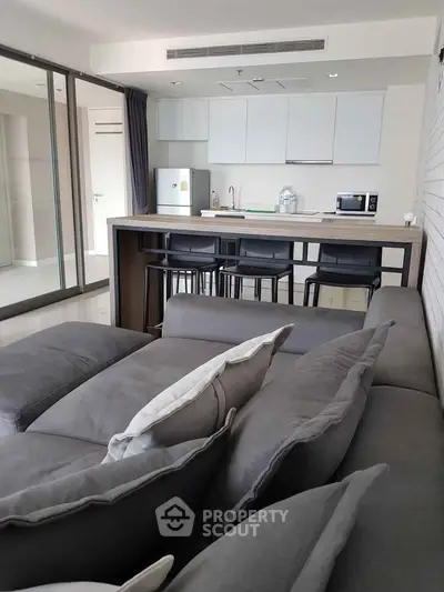 Modern open-layout living room with sleek kitchen and stylish gray sofa