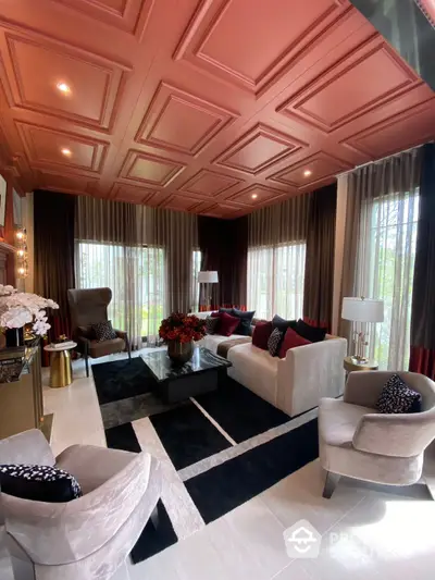 Opulent living room with rich red coffered ceiling, elegant white sofas, and floor-to-ceiling windows offering ample natural light.