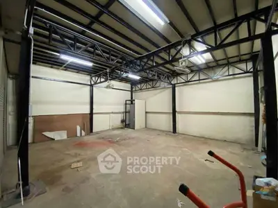 Spacious industrial-style room with high ceilings and metal beams, ideal for creative workspace.