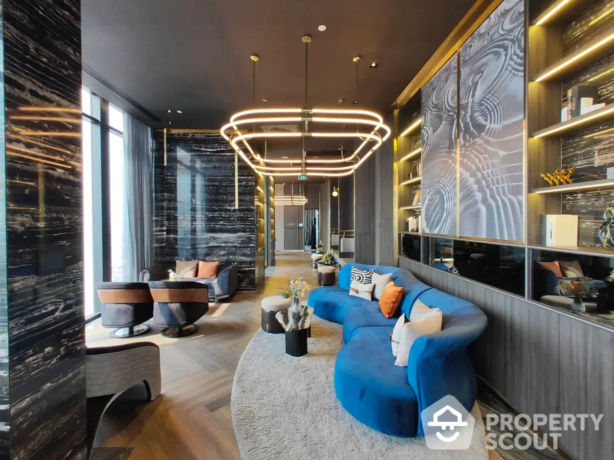 Luxurious living room with bold blue sofa, modern art, and elegant lighting fixtures, surrounded by sleek black marble walls and warm ambient lighting.