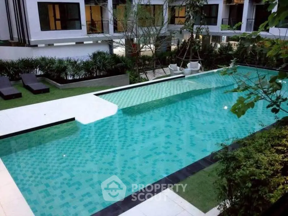 Luxurious modern apartment complex with a stunning outdoor pool and lush greenery.