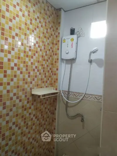 Compact bathroom with colorful mosaic tiles and modern shower heater