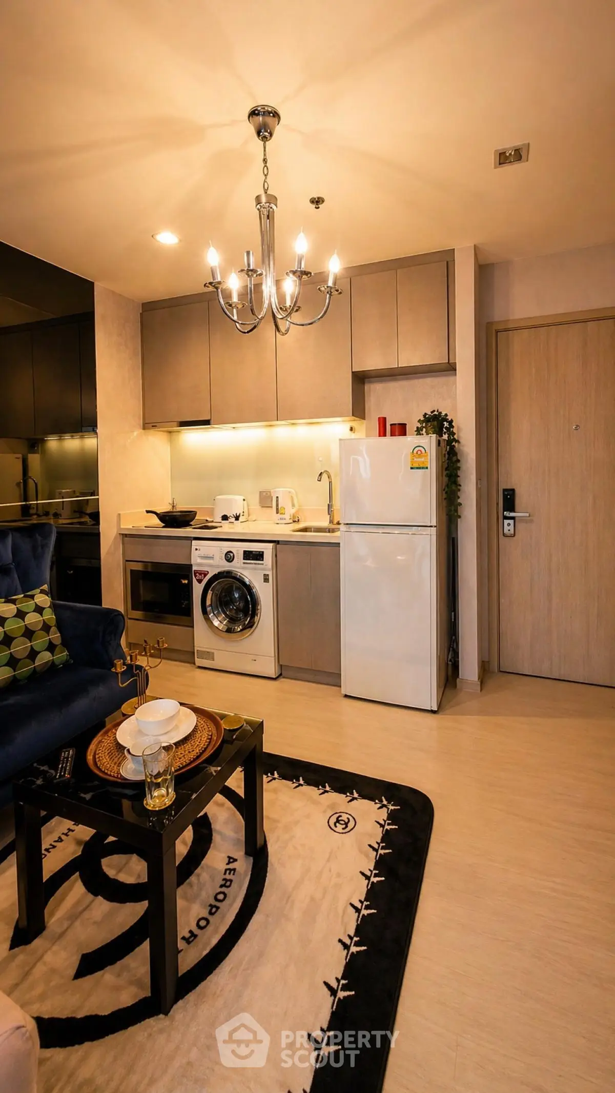 Modern kitchen with chandelier, washing machine, and fridge in cozy apartment
