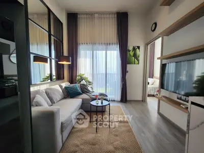 Modern living room with stylish decor and natural light, featuring a cozy sofa and wall-mounted TV.