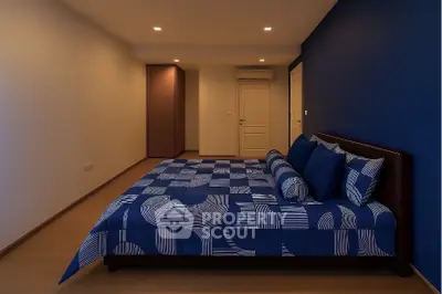 Spacious modern bedroom with stylish blue bedding and minimalist design.