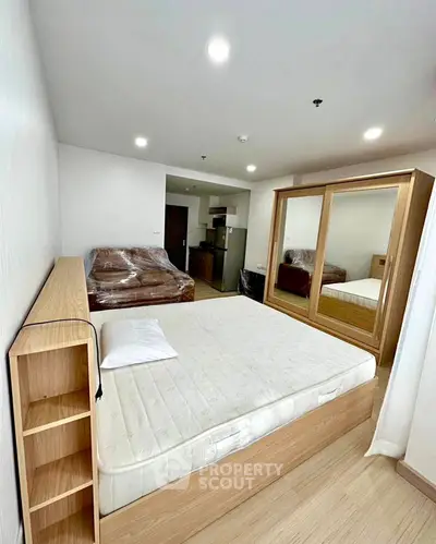 Modern bedroom with wooden furniture and mirrored wardrobe in a cozy apartment.
